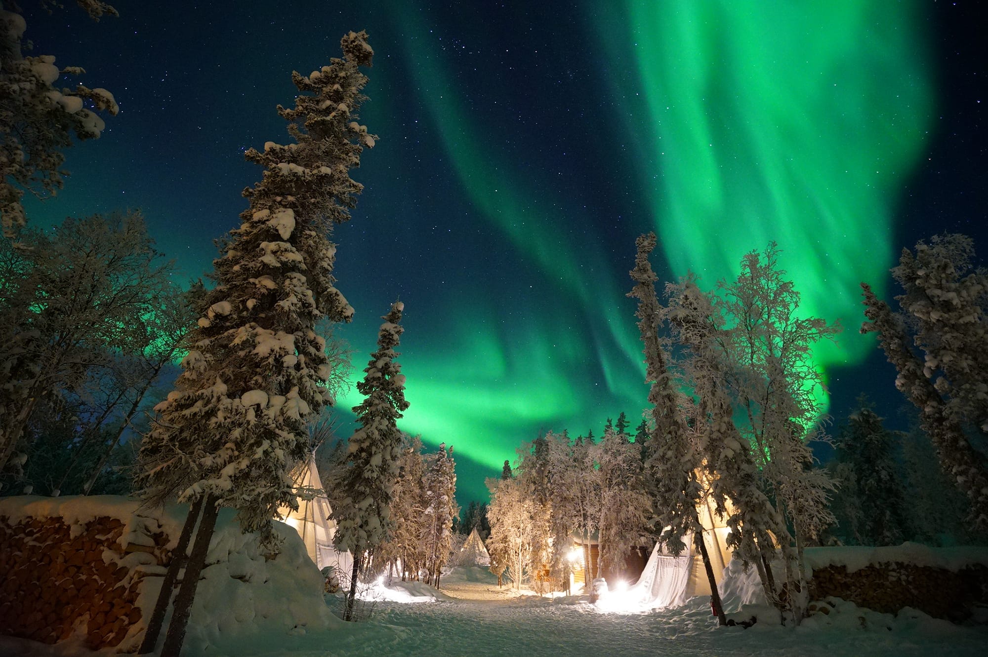 Watching the Aurora Borealis Northern Lights winter wonderland from the Aurora Teepee Village at Yellowknife, Northwest Territories, Canada.