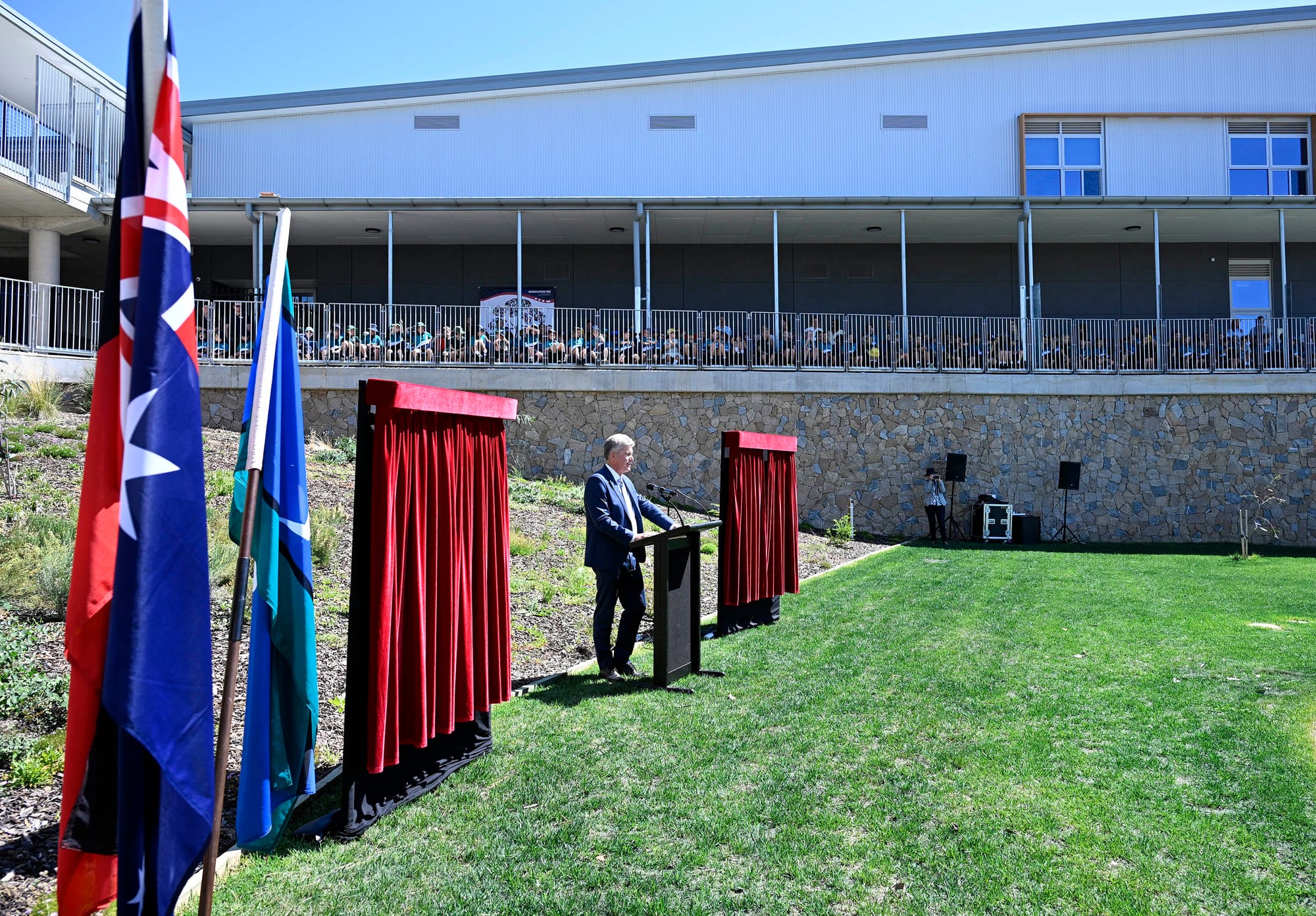 Primary school kids sit in the balcony above the opening ceremony as Steve Whan speaks.